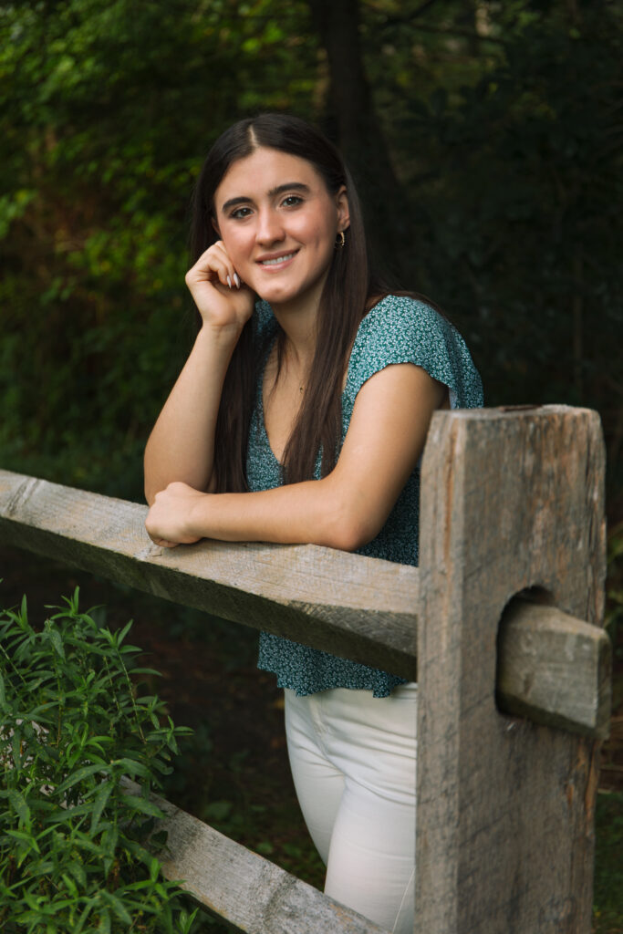 High school senior leaning on wooden fence.