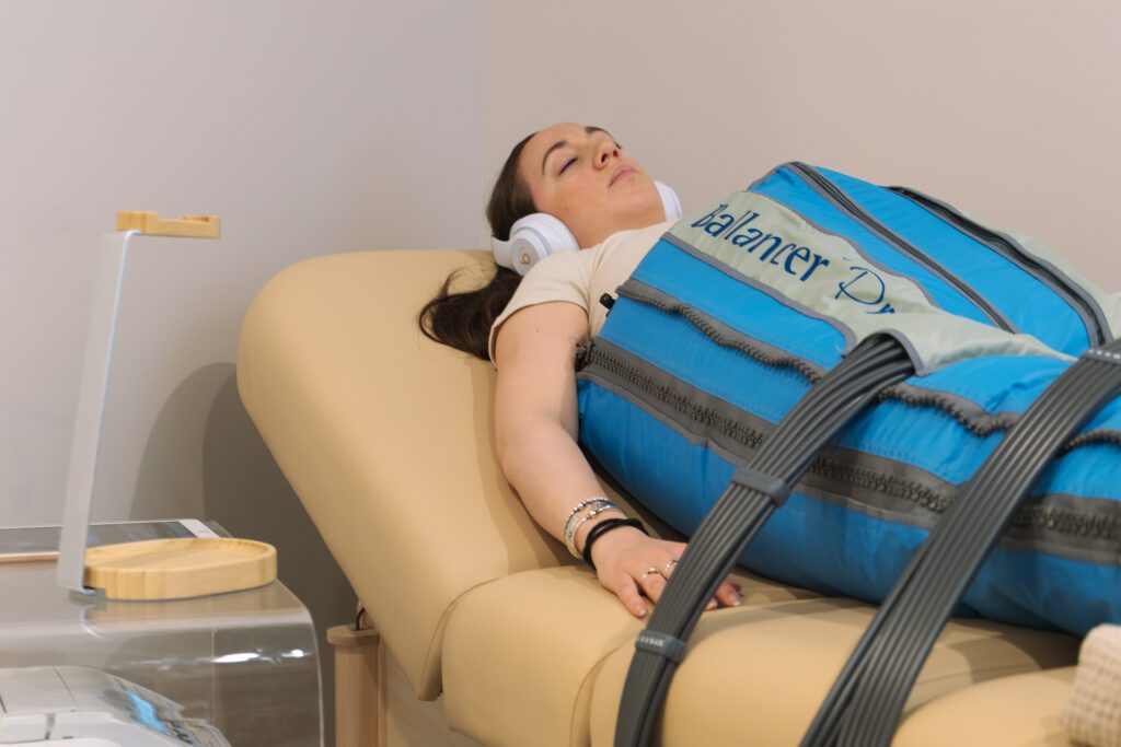 Woman in BalancerPro lymphatic drainage suit and hedaphones laying down for branding photography session in Revival Wellness Studio in Medfield, Massachusetts.