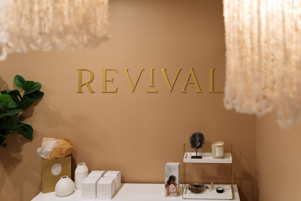 Revival Wellness Studio front desk with sign on wall and shelf of brochures and products for branding photography session in Medfield, Massachusetts.