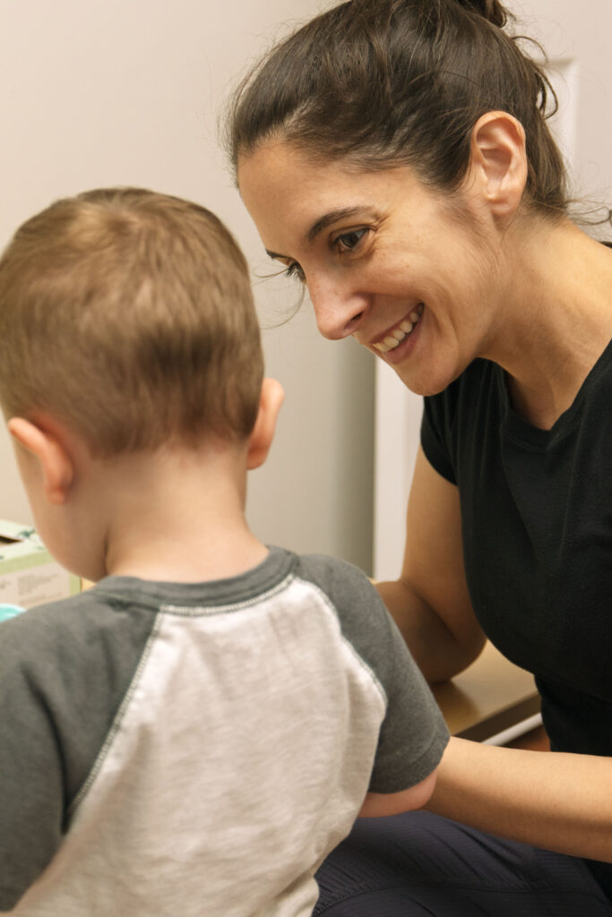 Owner, Jenna, smiling at child patient during brand photoshoot with Emma Lula Creative in Medfield, Massachusetts.
