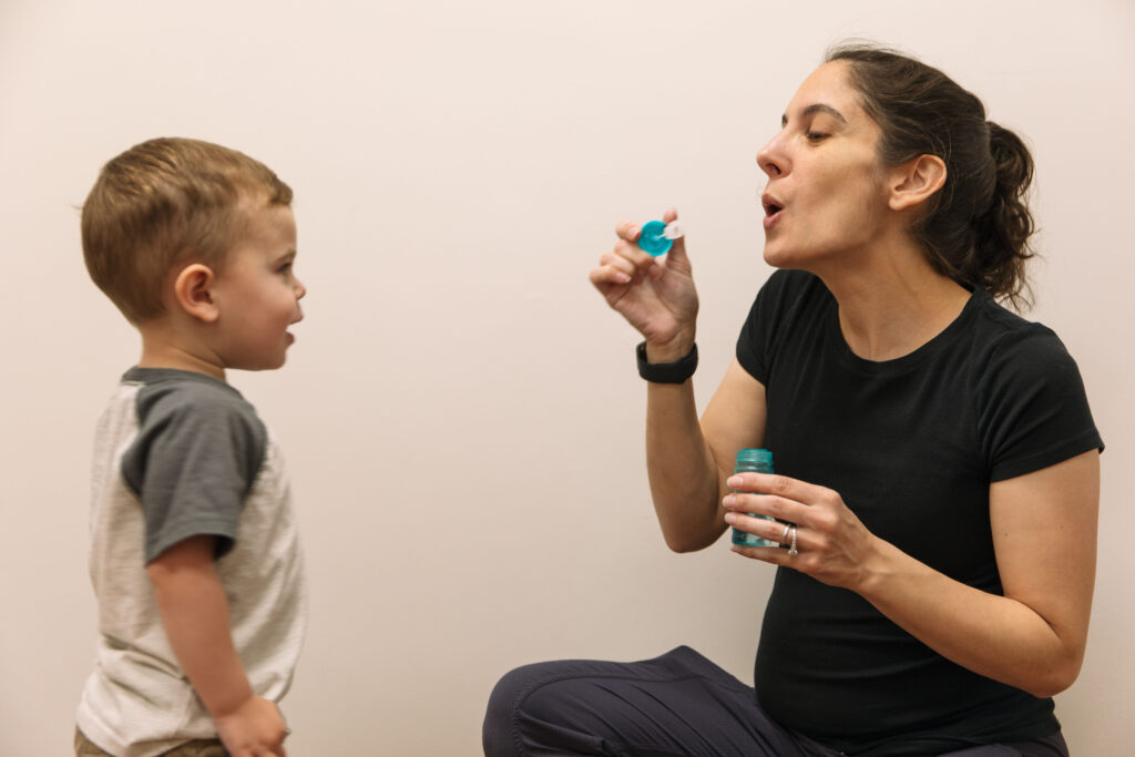 Raheb Physical Therapy brand photoshoot with owner blowing bubbles for child patient.